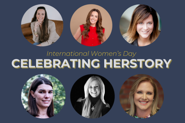 Promotional graphic for International Women's Day featuring six women in a circular arrangement. The text in the center reads 'International Women's Day CELEBRATING HERSTORY.' The women are dressed in various outfits, and the background is a solid dark blue color.