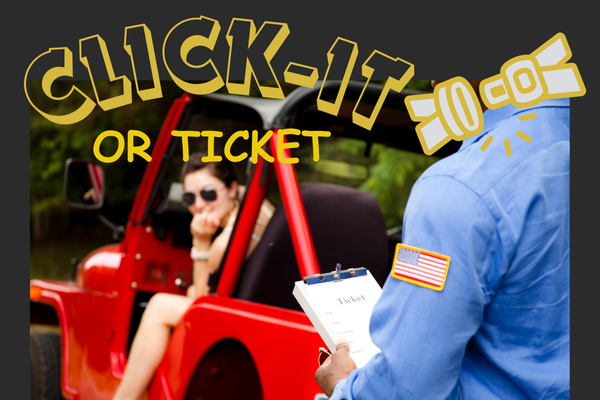 A police officer in a blue uniform is holding a clipboard with a ticket while standing next to a red vehicle. The driver inside the vehicle is blurred. The text "CLICK-IT OR TICKET" is prominently displayed at the top, accompanied by an illustration of a seatbelt. The image emphasizes the importance of wearing a seatbelt to avoid receiving a ticket.